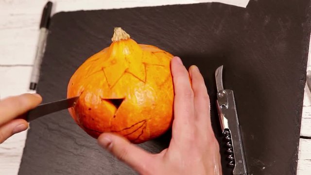 A person carves the Halloween pumpkin as drawn beforehand