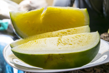 half slices of  yellow watermelon without bones on a wooden background a plate