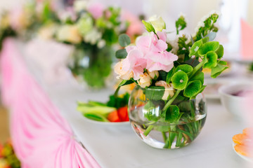 A round transparent vase with a flower arrangement on a table wi