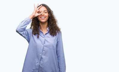Young hispanic business woman doing ok gesture with hand smiling, eye looking through fingers with happy face.