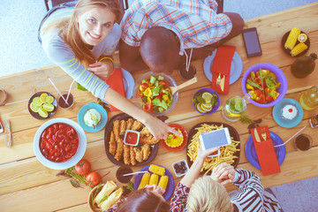 Top view of group of people having dinner together while sitting at wooden table. Food on the table. People eat fast food.
