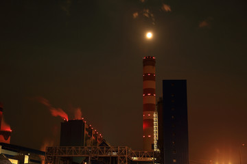 Elektrownia, fabryka w świetle księżyca w pełni nad kominem.