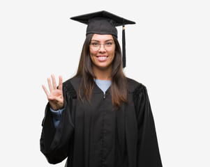 Young hispanic woman wearing graduated cap and uniform showing and pointing up with fingers number four while smiling confident and happy.