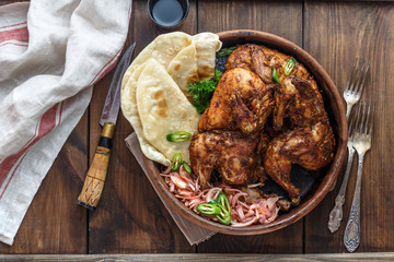 Tandoori chicken. Half of tandoori chicken served with lime slices and cilantro. Top view, blank space