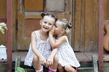 Fototapeta premium Two beautiful sisters are secret on the porch of the house