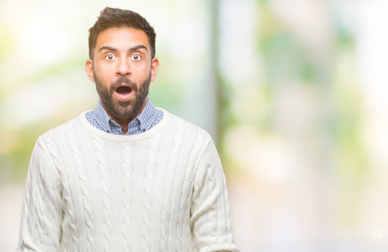 Adult hispanic man wearing winter sweater over isolated background afraid and shocked with surprise expression, fear and excited face.