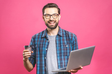 Confident business expert. Confident young handsome man with coffee in shirt holding laptop and smiling while standing against pink background