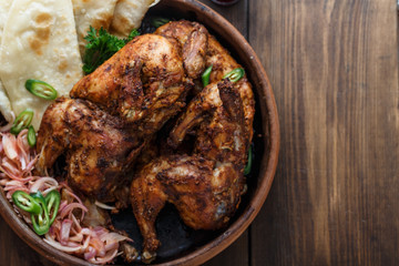 Tandoori chicken. Half of tandoori chicken served with lime slices and cilantro. Top view, blank space