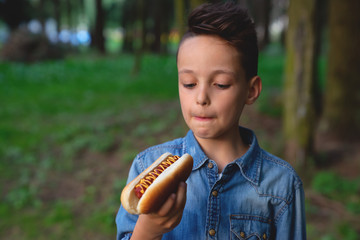 a young boy takes a bite of a hot dog