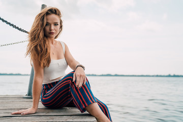 Woman sitting on dock in front of lake - 219862651