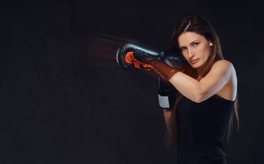 Beautiful brunette female boxer during boxing exercises, focused on a process with serious concentrated facial.