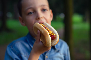 a young boy takes a bite of a hot dog