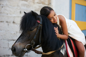 Happy young girl on countryside with horse. Young child with brown horse