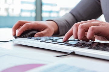 Finance professional working on keyboard with reports