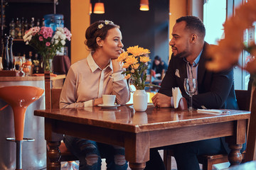 Happy attractive African-American couple in love having a great time together in a restaurant at their dating. A beautiful couple enjoying each other.