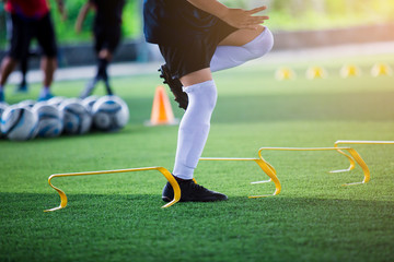 Kid soccer player Jogging and jump between marker and yellow hurdles. Soccer training.