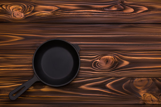 Cast iron frying pan on a wooden background. View from above. Kitchen tools