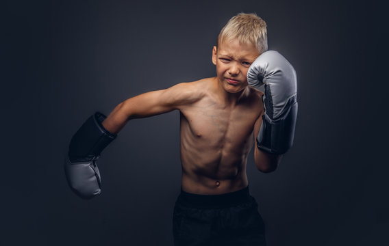 Shirtless young boxer with blonde hair wearing boxing gloves shows a boxing hook.