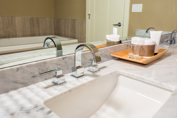 Fragment of a modern luxury bathroom with sink, wooden tray and large mirror. Interior design.