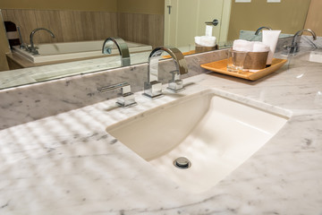 Fragment of a modern luxury bathroom with sink, wooden tray and large mirror. Interior design.