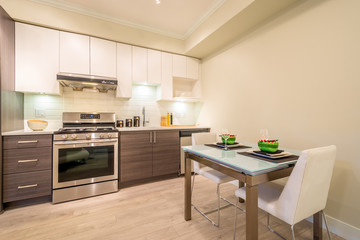 Modern, bright, clean kitchen interior with stainless steel appliances and dinner table in a luxury apartment.	