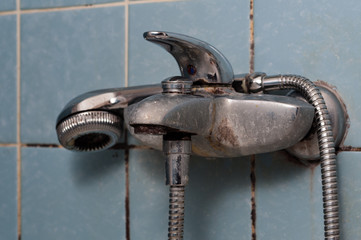 Calcified times, faucet and shower head in bathroom.