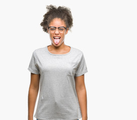 Obraz premium Young afro american woman wearing glasses over isolated background sticking tongue out happy with funny expression. Emotion concept.