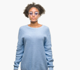 Young afro american woman wearing glasses over isolated background with serious expression on face. Simple and natural looking at the camera.
