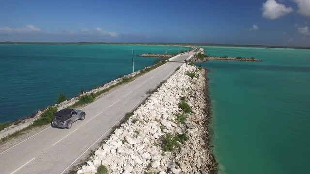 Aerial, car drives on tropical Turks and Caicos road