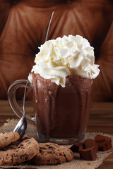 A messy cup with hot chocolate and chocolate chip cookies.