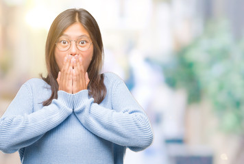 Young asian woman wearing winter sweater over isolated background shocked covering mouth with hands for mistake. Secret concept.