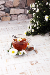 cup of tea with chamomile flowers on rustic background