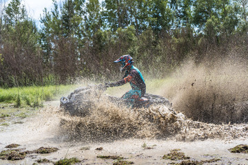 ATV Quad rides fast on big dirt and makes splashes of dirty water