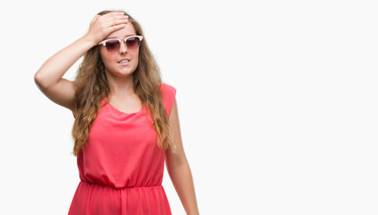 Young blonde woman wearing pink sunglasses stressed with hand on head, shocked with shame and surprise face, angry and frustrated. Fear and upset for mistake.