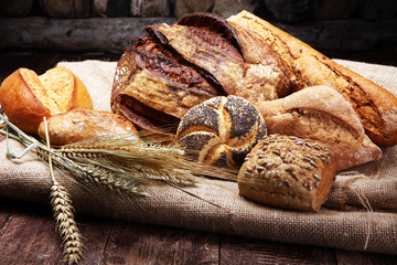 Different kinds of bread and bread rolls on wooden table