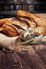 Different kinds of bread and bread rolls on wooden table