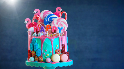 On-trend candyland fantasy drip cake with gift in birthday party setting.