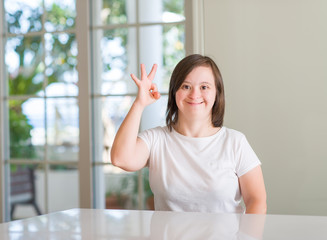 Down syndrome woman at home doing ok sign with fingers, excellent symbol