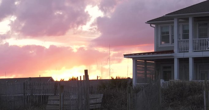 Low angle, sun sets over coastal home