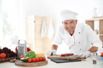 Professional chef cooking meat on table in kitchen