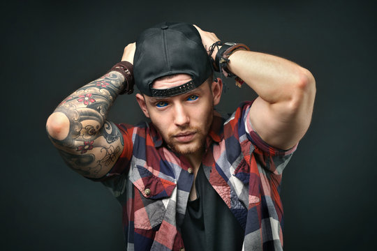 Young tattooed man posing on dark background