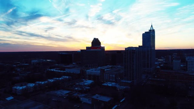 Sunset over Raleigh skyline, tilt down aerial