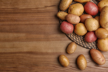 Flat lay composition with fresh organic potatoes on wooden background