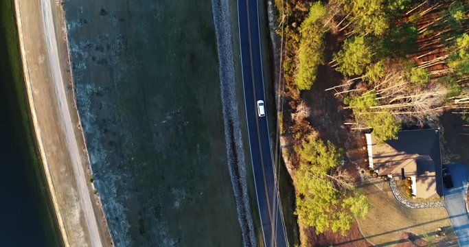 Car drives on rural road, overhead aerial