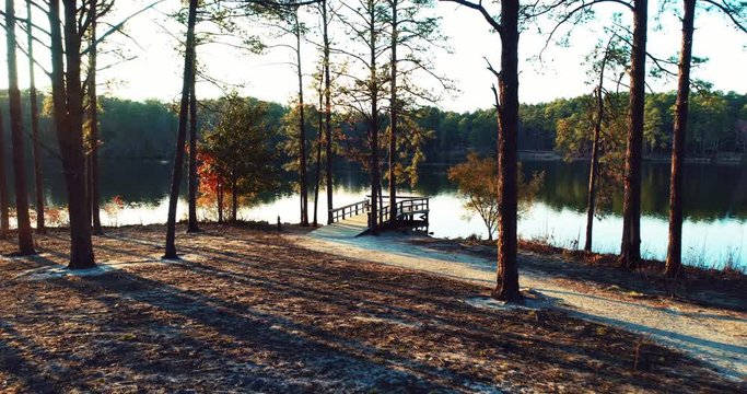 Aerial, sun shines over lake shore