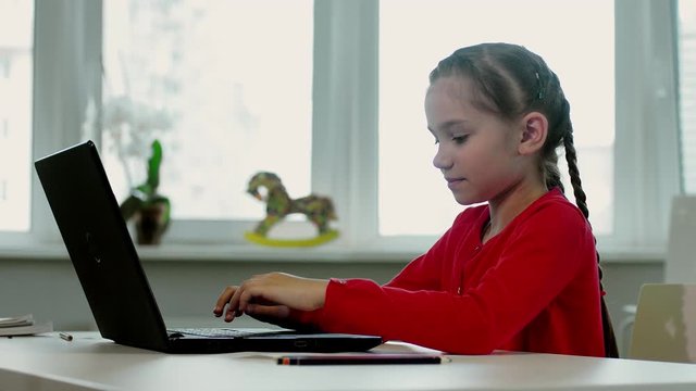 A little girl in red lingerie works behind a laptop