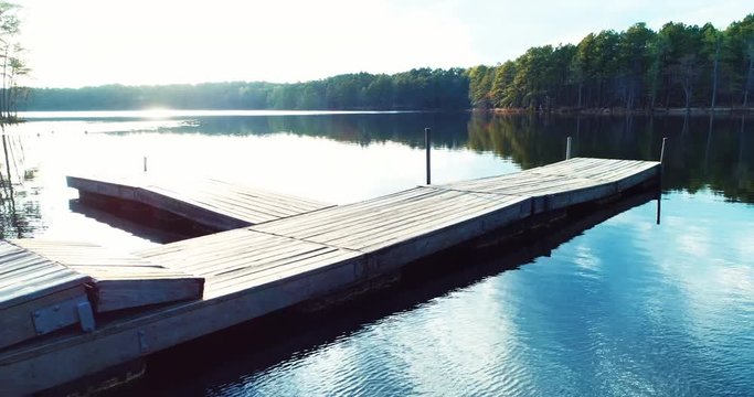 Aerial, sun shines on lake dock