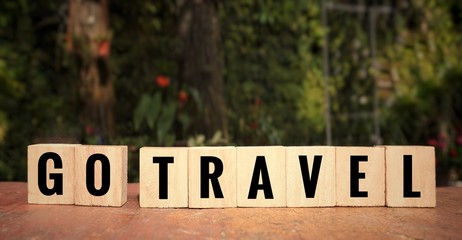 Motivational and inspirational quote - ‘GO TRAVEL’ written on wooden blocks. Blurred styled background.