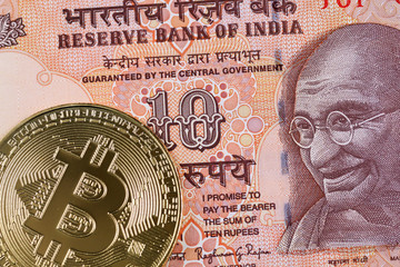 A golden bitcoin with an orange 10 Indian rupee bank note in macro
