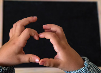 student hands making a heart detail on a blackboard